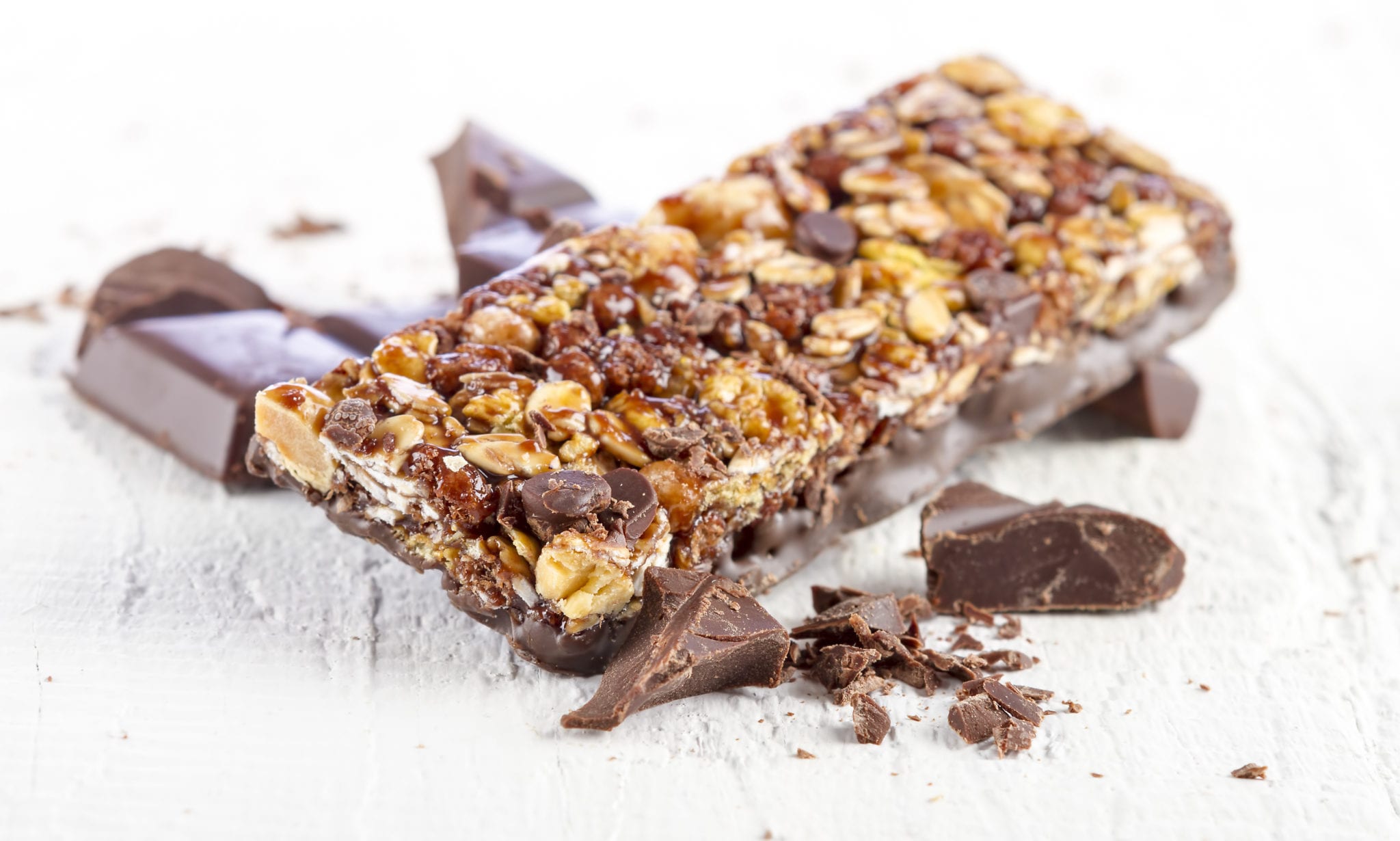 granola bar with chocolate on white wooden background